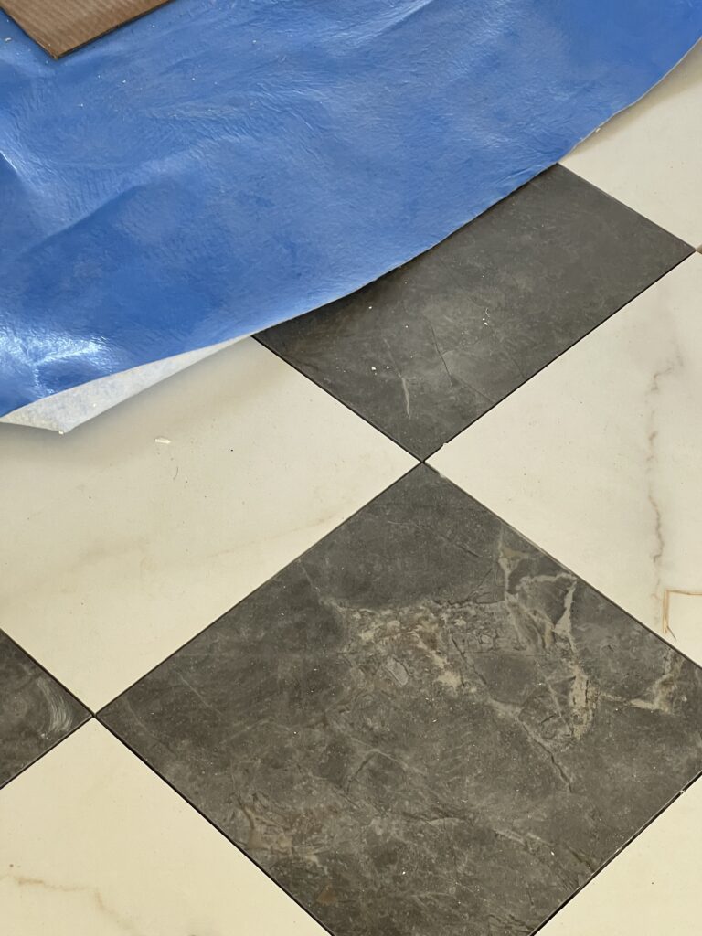 In-progress checkered floor tile installation in a Rock Spring spec home, adding a classic pattern to the home’s updated traditional design
